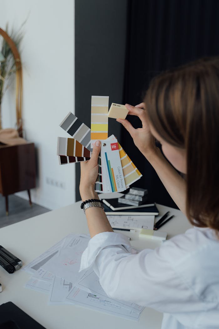 Professional interior designer examining color sample swatches at a workspace desk.